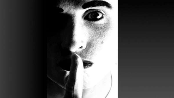 Schwarz-weißes Porträt eines Gesichts mit erhobenem Zeigefinger vor dem Mund Stille, Körpersprache, Schweigen, Ausdruck, Mimik, Kommunikation