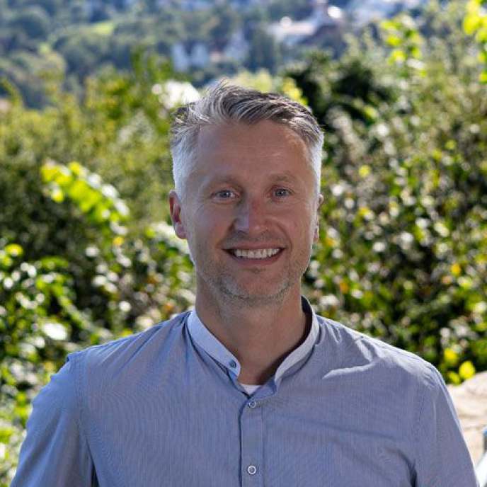 junger Mann, blaues Hemd, draußen, Mauer im Hintergrund