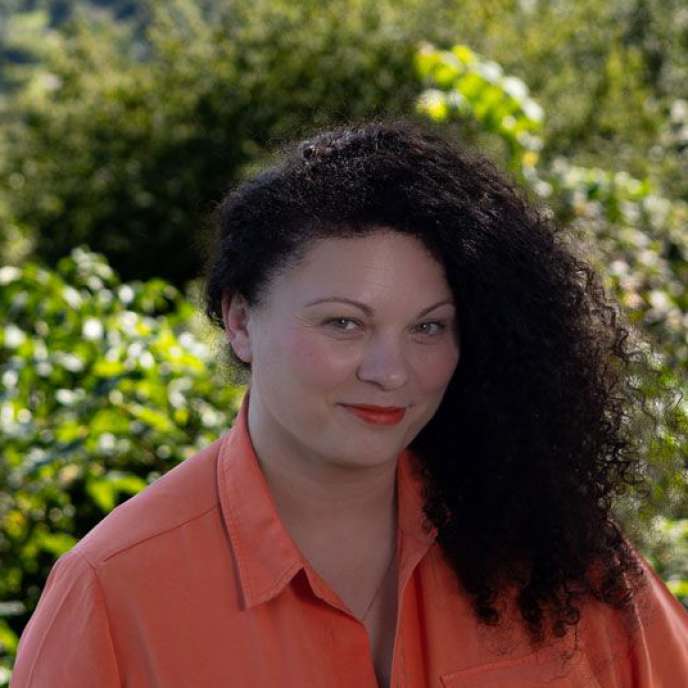  junge Frau, oranges Oberteil, draußen, fröhliches Gesicht
