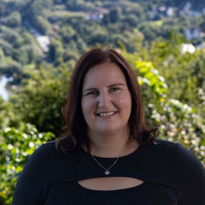  junge Frau, blaues Oberteil, draußen, fröhliches Gesicht