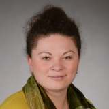 Frau mit freundlichem Lächeln blickt symphatisch in die Kamera