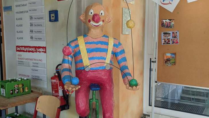  Bunte Clown-Figur auf einem Einrad mit Jonglierbällen 