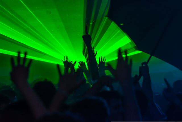  Menschen tanzen im dunklen Club unter grünen Laserlichtern