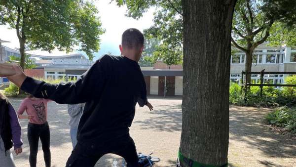 Ein Schüler balanciert mit Unterstützung seiner Gruppe teamübung, gruppendynamik, gleichgewicht, slackline, schülertraining,