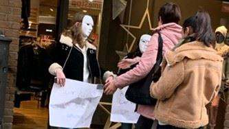  Zwei Personen mit weißen Masken und Schildern 